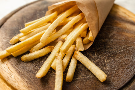 Portion of french fries on catering platter. Closeup of paper pack with traditional american fried...