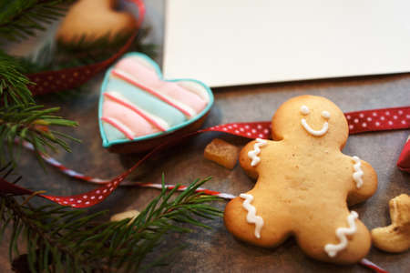 Gingerbread man and heart with blank greeting card. Top view on table with handmade surprise, sweet present for holiday, free space. Handmade gift, homemade pastry, love conceptの写真素材