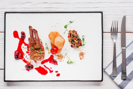 Restaurant serving of grilled ribs flat lay. Top view on white tray with meat, potato and vegetable mix with cherry sauce and cutlery. Expensive food, luxury lifestyle, recipe conceptの写真素材