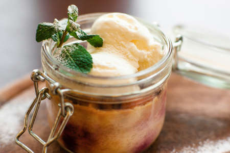 Homemade ice-cream in glass jar close-up. Natural colorful dessert decorated with mint, free space. Confectionery, hobby, organic food conceptの写真素材