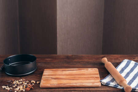 Clean workplace of baker with tools free space. Kitchen table with wooden board, pin, pie form and dry fruits waiting for confectioner, copy space for textの写真素材