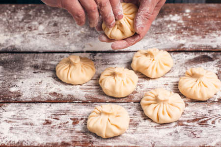 Handmade cooking of khinkali at kitchen. Cook prepares national georgian meal with dough and meat, cooking process. Traditional cuisine, kitchen conceptの写真素材