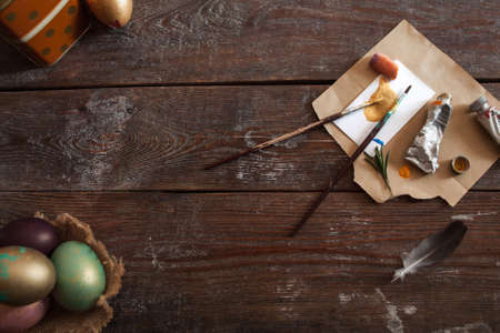 Art tools and colorful Easter eggs flat lay. Top view on rustic dark wooden background with dye and paintbrushes, after decorating eggs for holiday. Creative, handmade decoration, tradition conceptの写真素材