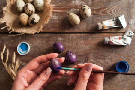 Preparing for Easter holiday flat lay. Top view on hands coloring eggs to purple. Handmade...
