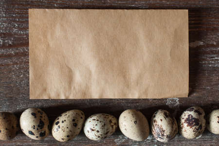 Blank vintage paper with quail eggs flat lay. Top view on empty brown card with raw eggs, free space for text. Holiday, Easter, culinary, recipe, dietary conceptの写真素材