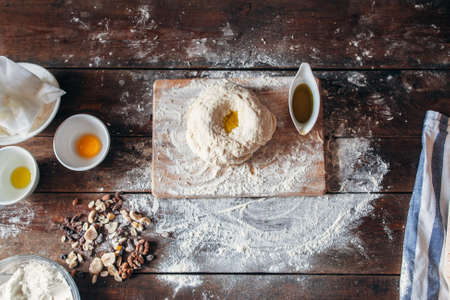 Raw dough with oil on kitchen table flat lay. Top view on baker workplace with ingredients for making bread with dry fruits. Bakery, recipe, cooking conceptの写真素材