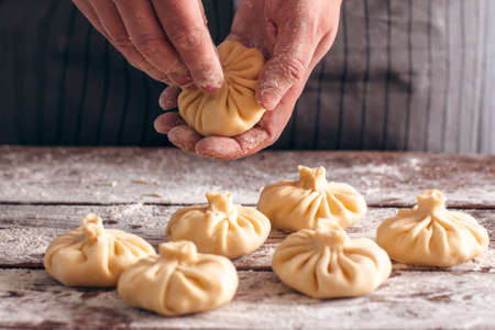 Cook preparing khinkali at kitchen close-up. Process of making traditional georgian meal, handmade cooking. National cuisine, kitchen, food conceptの写真素材