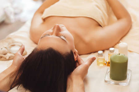 Woman with migraine relaxing at salon free space. Brunette having treating massage. Alternative medicine, health care, headache conceptの写真素材