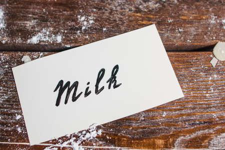 Card with word milk on table flat lay. Top view on old wooden desk with name of natural drink. Kitchen, recipe, cooking, food ingredient conceptの写真素材