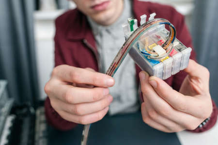 Colorful cartridge refilling at office closeup. Unrecognizable man fixing ink-jet supply system, free space for text. Equipment, business, electronic conceptの写真素材
