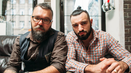 Hipster and biker sitting together portrait. Two bearded men with different hobbies, but similar...