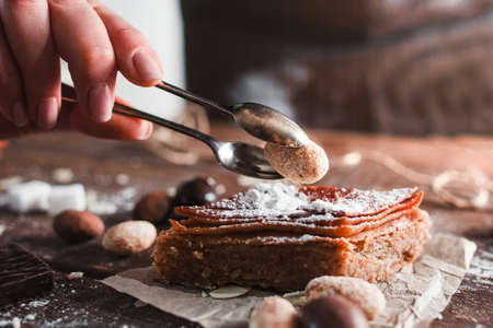 Decorating turkish dessert with nut closeup. Side view on confectioner hand putting almond on baklava, free space. Pastry, eastern sweet conceptの写真素材