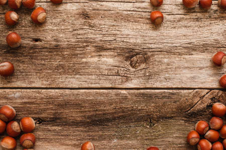 Wooden background with hazelnuts frame flat lay. Top view on rustic table with brown filbert nuts border, free space, bright autumn backdrop. Harvest, fall, food ingredient conceptの写真素材
