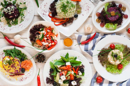 Assortment of fresh vegetable salads flat lay. Top view on vegetarian buffet with tasty side dish variety. Healthy food set, organic, natural eating conceptの写真素材