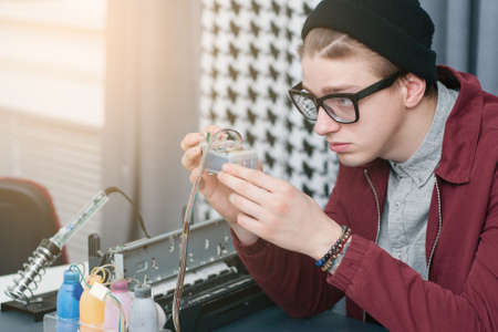 System administrator refilling cartridge free space. Side view at young man fixing continuous ink supply system for printer. Office equipment, cmyk, business, electronic conceptの写真素材