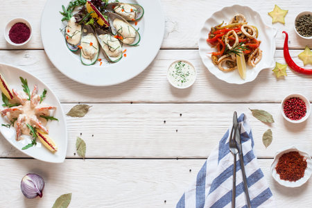 Mediterranean snacks with cutlery flat lay. Top view on white wooden table with variety of appetizing seafood meals, free space. Gourmet, luxury lifestyle conceptの写真素材