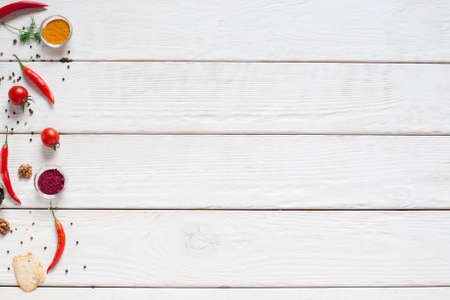 White wooden table with red seasoning frame flat lay. Dried paprika, chili peppers and tomatoes on kitchen table, free space with red spices.の写真素材