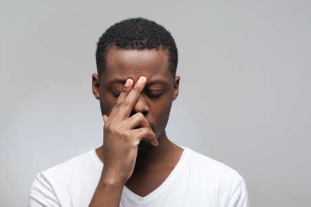 Thoughtful young african american man with closed eyes on grey background with free space for text.の写真素材