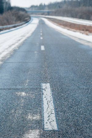 Winter empty highway with a dashed white line in a daytime. Blurred background of winter urban...
