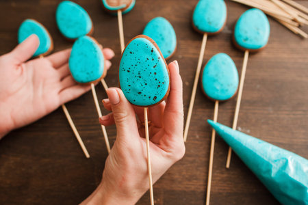 Preparing easter cookies with blue icing for decoration on rustic wooden table top view