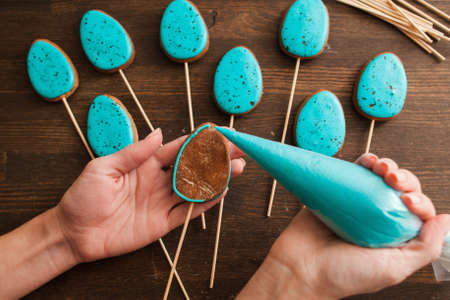 Handmade easter sweets for decoration. Preparing cookies with blue icing for decoration on rustic wooden table top viewの写真素材