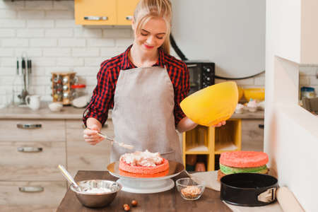 Woman preparing a sweet homemade cake on kitchen wooden table. Blogger, birthday celebration , small business, delivery of sweets , culinary craftsmanship, good housewife conceptの写真素材