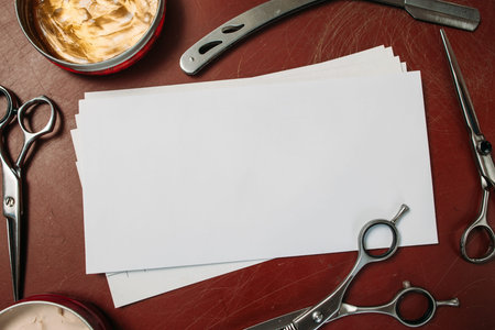 Blank card with scissors and razor flat lay. Top view on red table with shaving and cutting instruments, free space for text. Beauty, barbershop, manhood conceptの写真素材