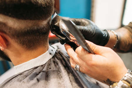 Man making curly haircut at barber shop closeup. Stylist hand with trimmer cutting male head. Hairstyle, beauty, modern lifestyle, fashion conceptの写真素材