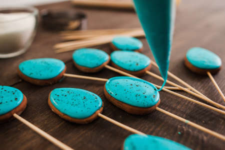 Preparing cookies with blue icing for decoration on rustic wooden table closeupの写真素材