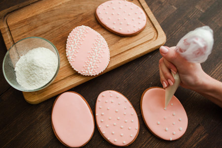 Decorating wedding pink cookies with white icing on rustic wooden table top viewの写真素材