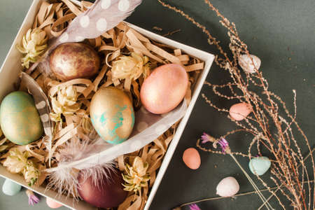 Handmade easter gift box with five color eggs, feathers and flowers on grey background. traditional festive foodの写真素材