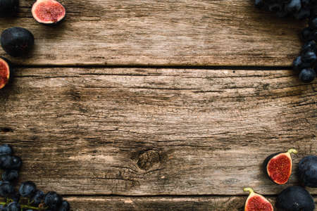 Grape and fig frame on mossy wood free space. Top view on old wooden background with ripe purple autumn fruit border. Autumn motives, harvest, gourmet conceptの写真素材