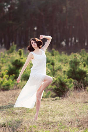 Contemporary dances in nature. Woman in flying white dress dancing in forestの写真素材