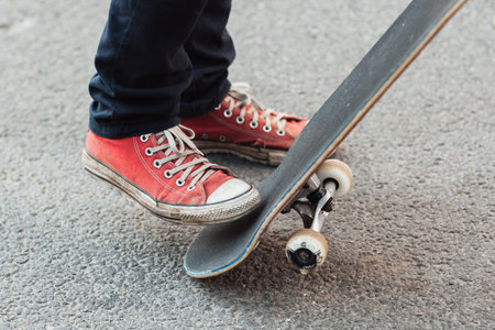 Skater doing flicking trick with skateboard tail. Level up skill. Streetwear style with red sneakers...