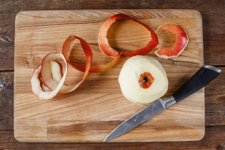 Top view of single red apple paring by knife. Fresh fruit lay on wooden desk. Healthy food, dietary, cooking conceptの写真素材