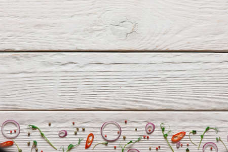 Various spices on white wood background. Sliced red onion, chili pepper and aromatic seeds with free space on deskの写真素材