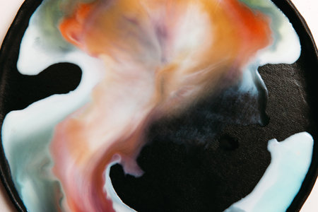 Abstract image of colorful streaks of liquid on black background. Watercolor blots of milk with...