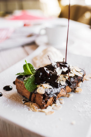 Decoration of chocolate pie by syrup. Delicious cake serving in restaurant with ice-cream ball and...