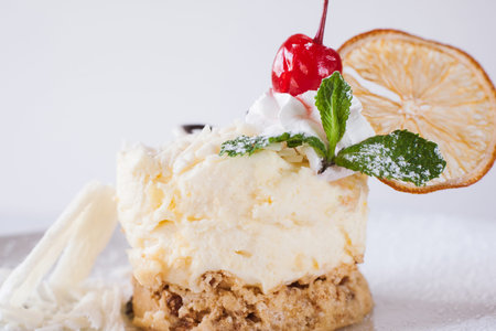 Creamy orange dessert serving on white background in restaurant. Delicious cake decorated by dried...