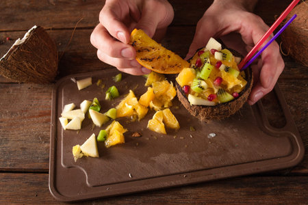 Decoration of tropical fruit salad in coconut shell. Apple, orange, kiwifruit and pomegranate...