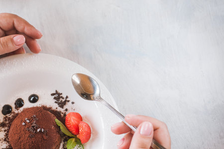 Tasting of delicious chocolate dessert for real gourmet. Customer eats fondant with decoration from strawberry and mint in restaurant, close up picture with free spaceの写真素材