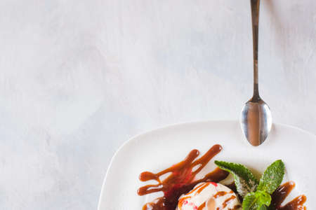 Sweet ice cream balls with caramel syrup serving in restaurant. Delicious cold dessert decorated fresh mint leaf, top view picture with free space on white backgroundの写真素材