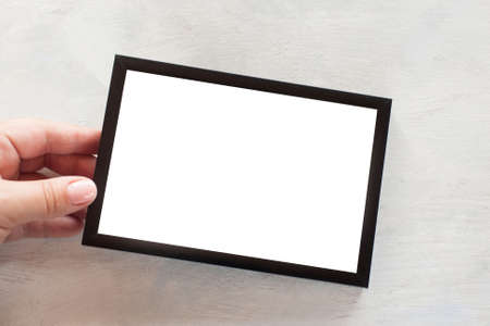Blank photo frame holding in hand on white background. Greetings, concept of tendance and family memories, close up picture with copy spaceの写真素材