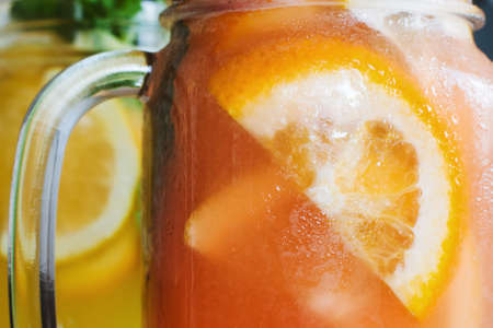 Background of fresh cold strawberry cocktail in jar. Close up picture of glass wall of fruit drinks with drops of water, sliced orange shape and mint, refreshment and coolness conceptの写真素材
