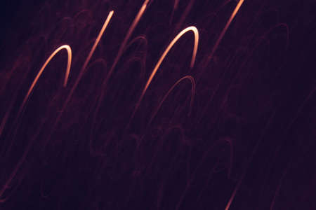Abstract background of yellow lines in motion on black wallpaper. Bokeh of defocused curves, blurred neon leds, festive or business backdrop of city lights, holidays and festivalsの写真素材