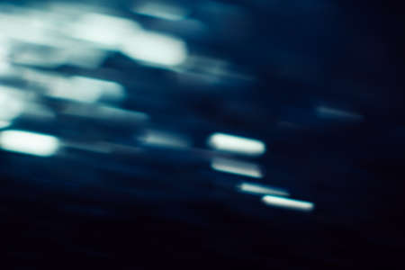 Abstract background of defocused white lights motion blur. Glowing urban backdrop, heavy night illumination city glimmers, bokehの写真素材