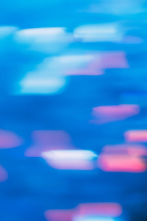Abstract background of defocused light motion. Blurred effect of urban glowing pink and white illumination on blue backdrop, shimmering city lights, wallpaper of festive decoration conceptの写真素材