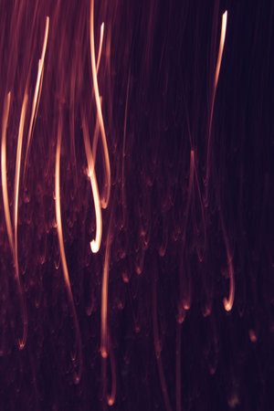 Abstract background of yellow lines in motion on black. Bokeh of defocused vertical curves, blurred neon leds of serpentine, festive backdrop of holidays, fireworks and celebrationsの写真素材