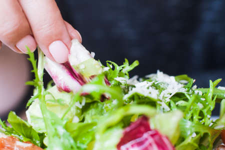 Woman eating green salad on plate by hand. Ruccola and cabbage with grated cheese, healthy nature food, dieting menu, close up pictureの写真素材
