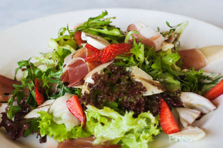 Salad lettuce with parma ham, blue cheese and strawberry serving in restaurant. Gourmet cuisine, close up pictureの写真素材